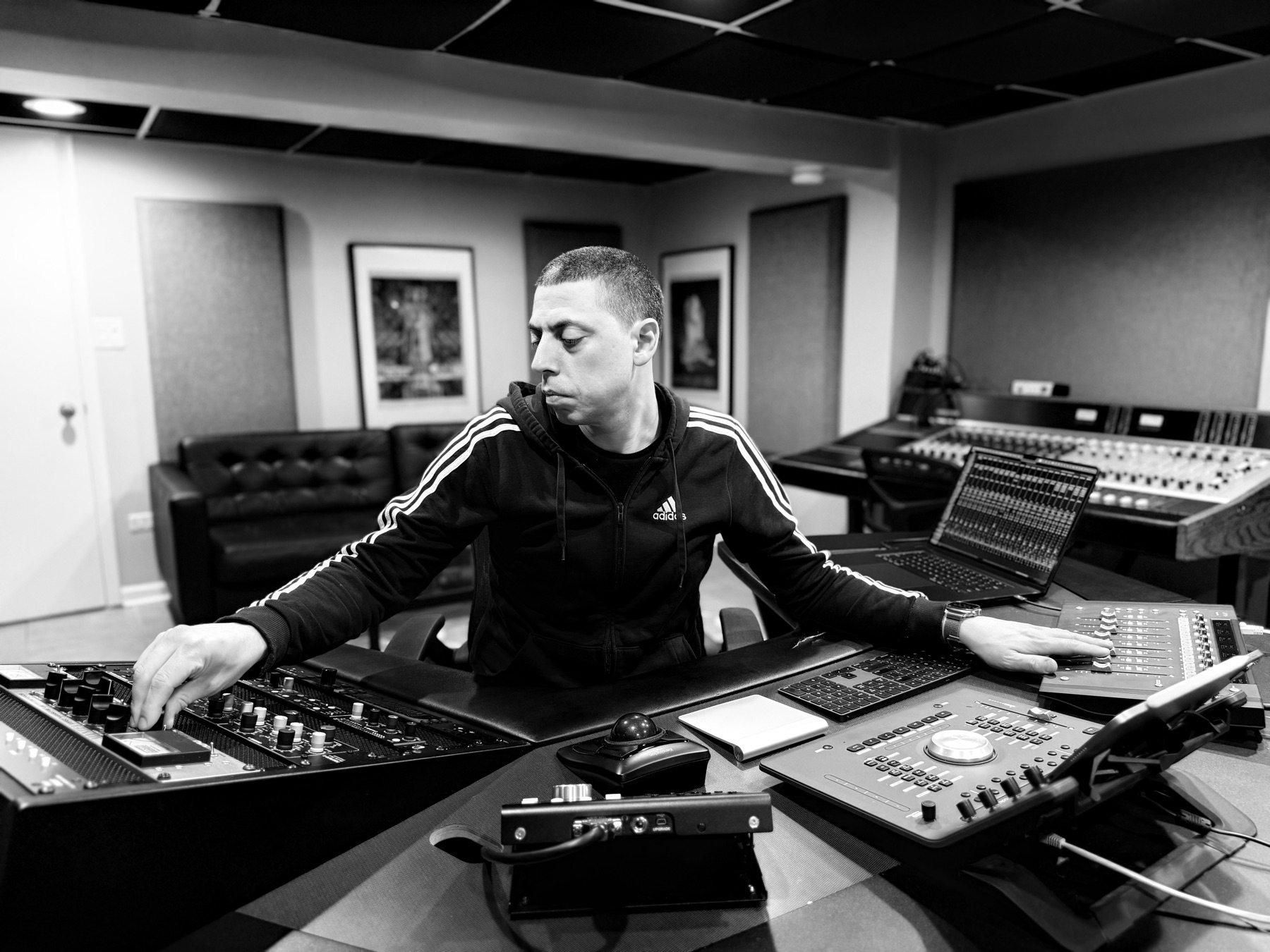 Chris Gelin at the console at Opus Audio Labs, one hand on the mastering desk and one on the monitor controller.